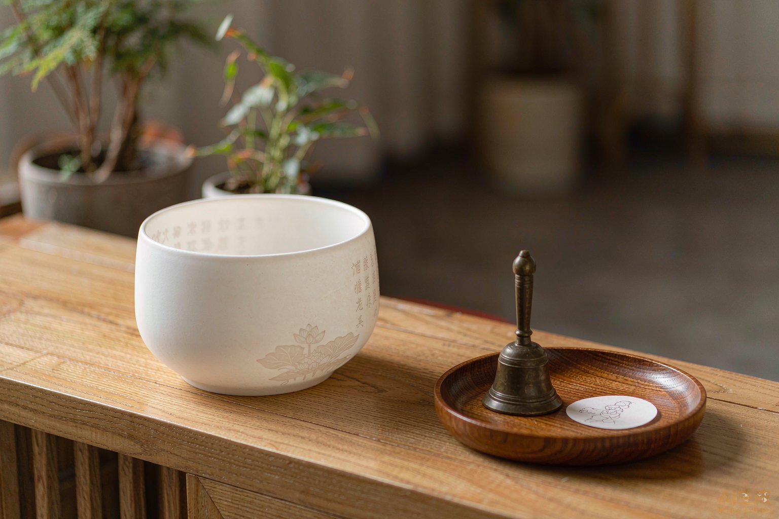 White offering bowl and small bell on a wooden meditation surface